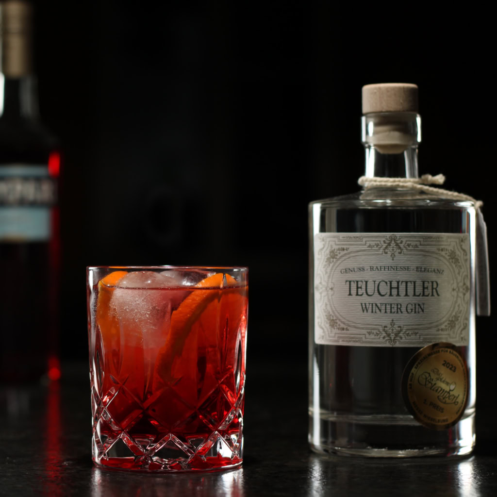 Klassischer Negroni Cocktail im Tumblerglas mit Eiswürfeln und Orangenscheibe